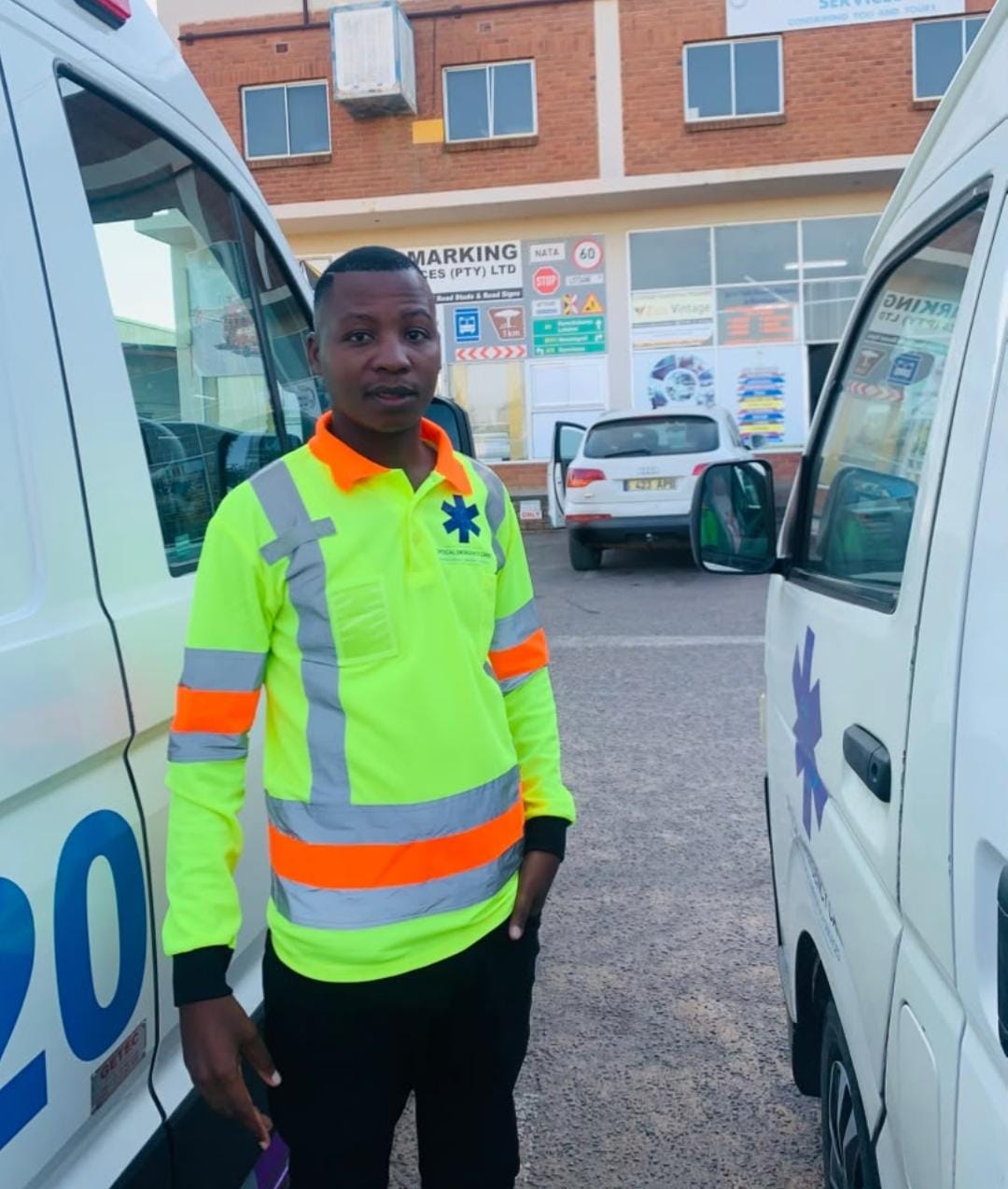 A medic in high-visibility uniform between two ambulances