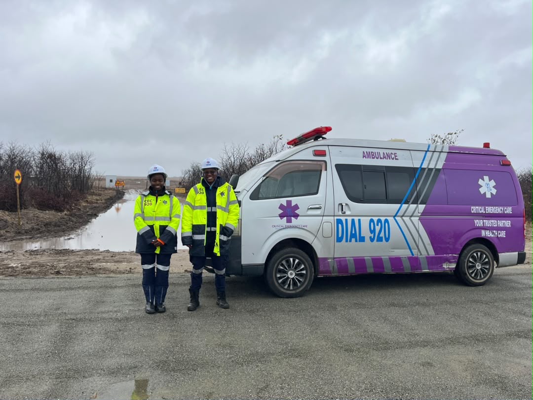 Two medics in hard hats beside a Dial 920 ambulance at a mine site